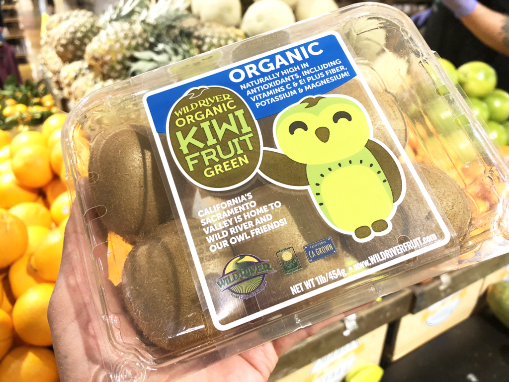 Our Owl Friends and associated kiwi owl logos are trademarks of Wild River Marketing Inc. Designed by Ben Young Landis and Guy Rogers. The photo shows a plastic clamshell container with six kiwifruits inside. The container's graphic shows the smiling Wild River green kiwi owl with one wing waving. Graphic says "California's Sacramento Valley is home to Wild River and Our Owl Friends!" and that the fruits are organic, naturally high in antioxidants, including vitamins C & E! Plus fiber, potassium & magnesium!