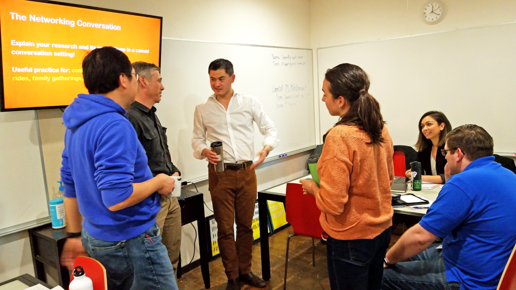 A scene from a "Connecting with Your Audience" Workshop taught by Ben Young Landis. Here, Ben Young Landis is leading a mock networking session with workshop participants Maxwell Leung, Rodd Kelsey, and Marissa Silva. Photo by Caleb B. Iversen/Creative Externalities. The four are standing in a circle holding drinks, playing the mock scenario of a conference reception.